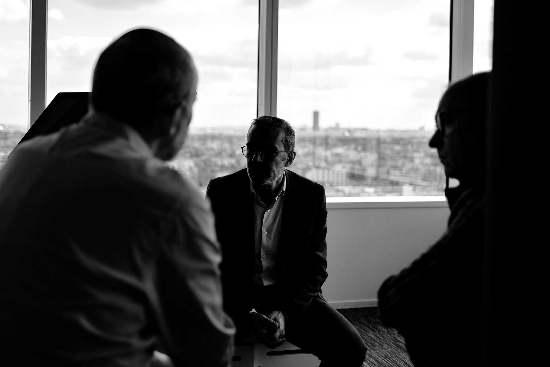 Three business men sitting together in an office with a few of a city skyline